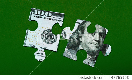 Pieces of a puzzle made from one hundred dollar bills on a green background Pieces of a puzzle made from one hundred dollar bills on a green background 142765908