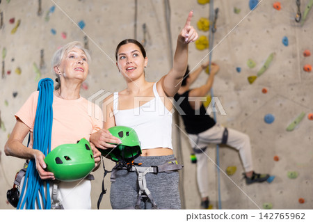 Confident female climbing instructor and her older trainee getting ready for training Confident female climbing instructor and her older trainee getting ready for training 142765962