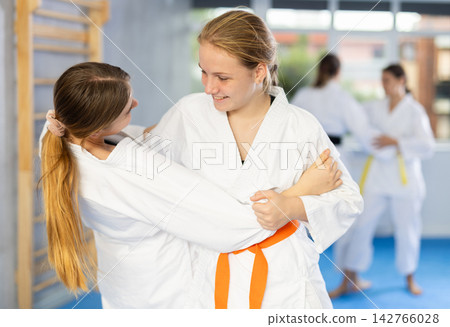 Female athletes in pair conduct training battle in oriental fighting technique Female athletes in pair conduct training battle in oriental fighting technique 142766028