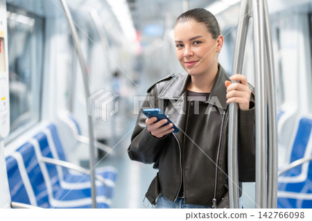 Young woman stands in subway car with phone Young woman stands in subway car with phone 142766098