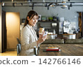 A young woman looking at her smartphone while eating breakfast at a cafe. 142766146