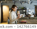 A young woman looking at her smartphone while eating breakfast at a cafe. 142766149