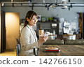 A young woman looking at her smartphone while eating breakfast at a cafe. 142766150