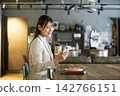 A young woman looking at her smartphone while eating breakfast at a cafe. 142766151