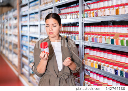 Female shopper choosing pottery glaze jars in pottery specialty store Female shopper choosing pottery glaze jars in pottery specialty store 142766188