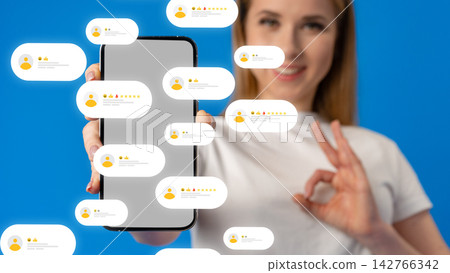 Woman holding smartphone with social media feedback in front of blue background Woman holding smartphone with social media feedback in front of blue background 142766342