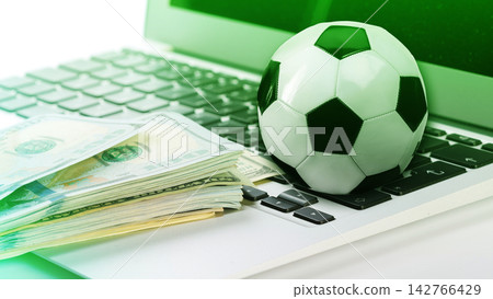 Betting on sports with cash and a soccer ball on a laptop keyboard Betting on sports with cash and a soccer ball on a laptop keyboard 142766429