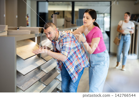 Couple man and woman choosing laminate flooring Couple man and woman choosing laminate flooring 142766544
