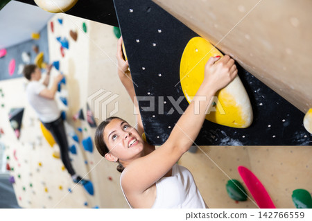Young woman practicing rock climbing on climbing wall Young woman practicing rock climbing on climbing wall 142766559