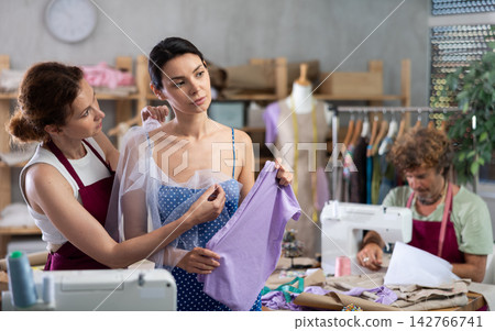 Female dressmaker applying textile on woman Female dressmaker applying textile on woman 142766741