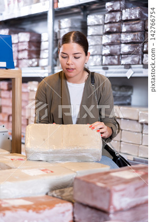 Young woman chooses pottery clay in shop Young woman chooses pottery clay in shop 142766754