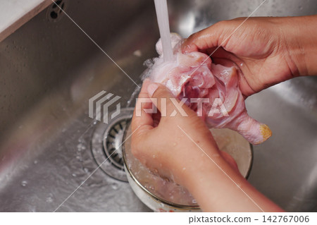 Washing chicken in a kitchen sink before preparing a meal Washing chicken in a kitchen sink before preparing a meal 142767006