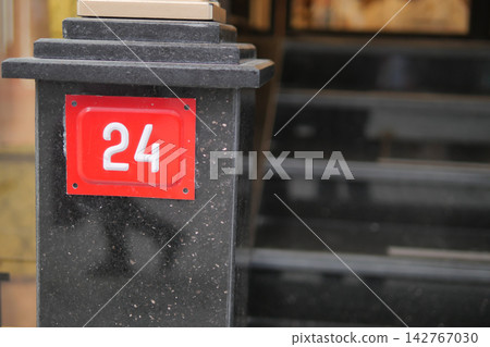 House number twenty-four near the entrance of a building in a city House number twenty-four near the entrance of a building in a city 142767030