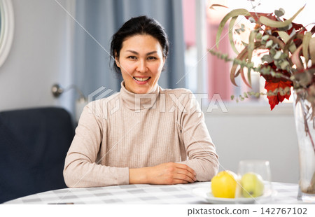 Portrait of positive woman sitting at table Portrait of positive woman sitting at table 142767102