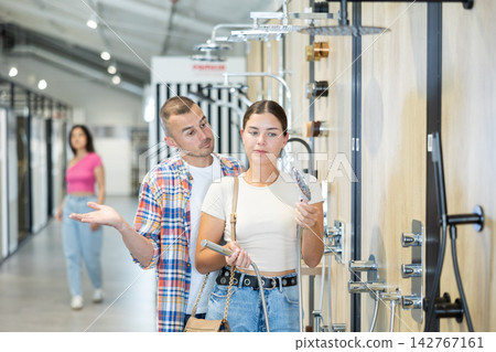 Positive couple selecting showerhead in bathroom fixtures store Positive couple selecting showerhead in bathroom fixtures store 142767161