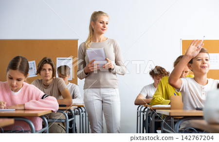 Classmates and female teacher working in groups to complete task during class Classmates and female teacher working in groups to complete task during class 142767204