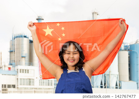 Happy young woman with flag of China against background of factory Happy young woman with flag of China against background of factory 142767477