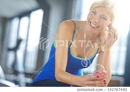 Earphones, sports and portrait of woman in gym listen to podcast, music or radio for training. Health, exercise and female athlete streaming song, album or playlist for workout in fitness center. Earphones, sports and portrait of woman in gym listen to podcast, music or radio for training. Health, exercise and female athlete streaming song, album or playlist for workout in fitness center. 142767480