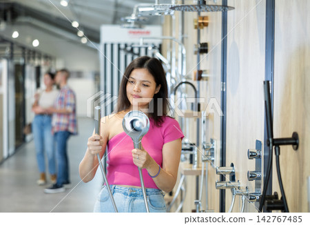 Young woman choosing shower head in store Young woman choosing shower head in store 142767485