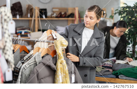 Woman browsing goods items and choose elect something autumn outwear Woman browsing goods items and choose elect something autumn outwear 142767510