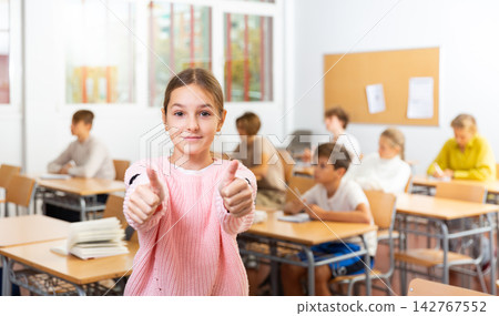 Portrait of positive teenager girl standing in classroom Portrait of positive teenager girl standing in classroom 142767552