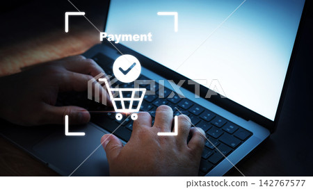 Hands making an online payment on a laptop with a shopping cart icon on the screen Hands making an online payment on a laptop with a shopping cart icon on the screen 142767577