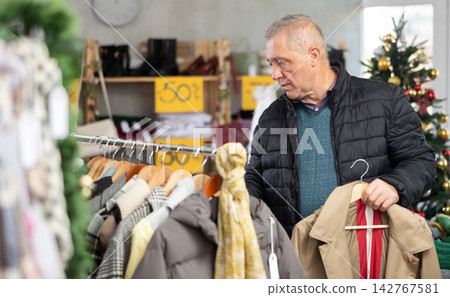Attentive mature man choosing jacket in clothing store Attentive mature man choosing jacket in clothing store 142767581