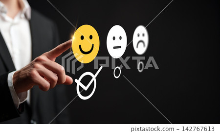 Person using a hand to select a happy face on a feedback survey with a dark background Person using a hand to select a happy face on a feedback survey with a dark background 142767613