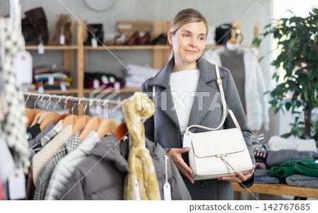 Adult woman choosing handbag in clothing store Adult woman choosing handbag in clothing store 142767685