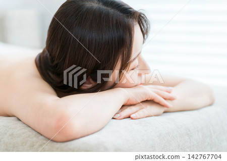 四五十歲的女性在美容院的護理床上閉著眼睛放鬆。 四五十歲的女性在美容院的護理床上閉著眼睛放鬆。 142767704