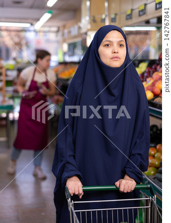 Woman in paranja with shopping cart in supermarket Woman in paranja with shopping cart in supermarket 142767841