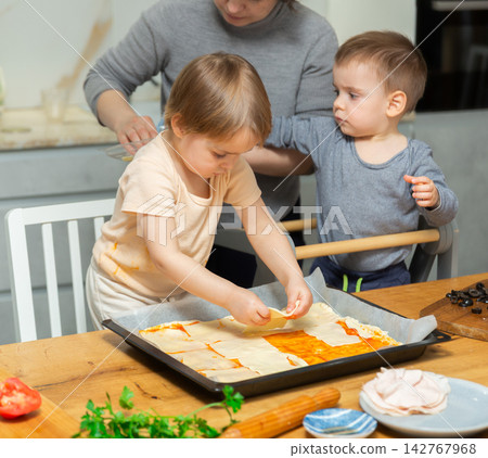 Mother and two young boys making pizza together in home kitchen Mother and two young boys making pizza together in home kitchen 142767968