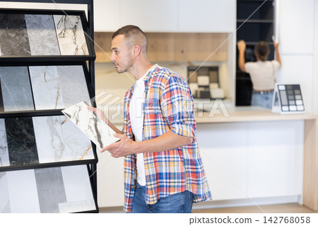 Young man chooses tiles in hardware store 142768058