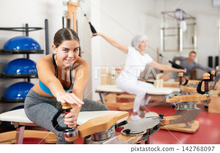 Young woman stretching her arms using pilates machine Young woman stretching her arms using pilates machine 142768097