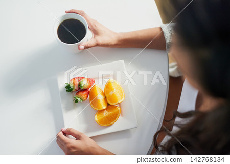 Fruit, coffee and above person with breakfast in morning for benefits of nutrition in diet. Healthy, food and woman drink espresso on table in home eating strawberry and orange with vitamin c Fruit, coffee and above person with breakfast in morning for benefits of nutrition in diet. Healthy, food and woman drink espresso on table in home eating strawberry and orange with vitamin c 142768184