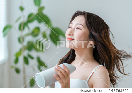 40-50歲女性在家用吹風機打造美麗髮型的護髮習慣。 40-50歲女性在家用吹風機打造美麗髮型的護髮習慣。 142768253