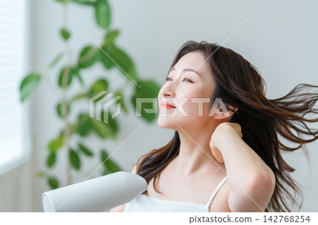 四、五十歲的女性正在用吹風機吹乾頭髮,照顧她們美麗的秀髮。 四、五十歲的女性正在用吹風機吹乾頭髮,照顧她們美麗的秀髮。 142768254