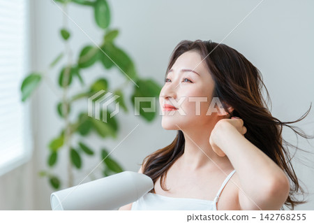一張美髮沙龍的照片,照片中一位四、五十歲的女性正在用吹風機打造漂亮的髮型。 一張美髮沙龍的照片,照片中一位四、五十歲的女性正在用吹風機打造漂亮的髮型。 142768255