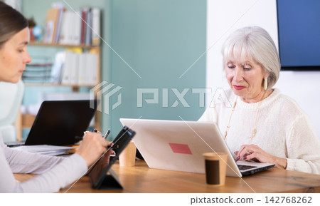 Two businesswomen work on laptops in modern company office Two businesswomen work on laptops in modern company office 142768262
