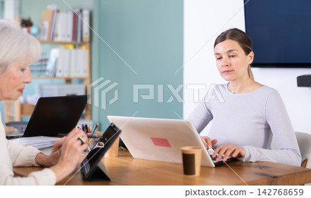 Two businesswomen work on laptops in modern company office Two businesswomen work on laptops in modern company office 142768659