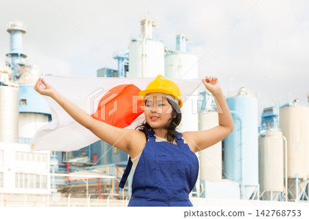 Portrait of smiling girl in construction overalls with the Japan flag on the background of modern factory Portrait of smiling girl in construction overalls with the Japan flag on the background of modern factory 142768753