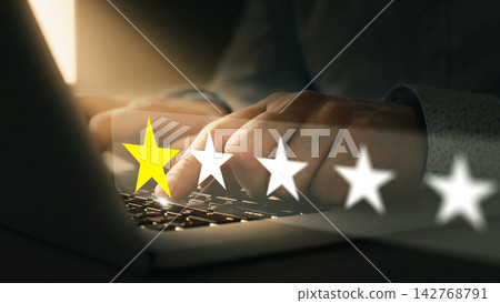 Person giving feedback rating on a laptop in a dimly lit room during evening hours Person giving feedback rating on a laptop in a dimly lit room during evening hours 142768791
