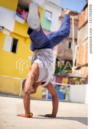 Capoeira, dance and man on street in Brazil for exercise, skill and entertainment in city. Martial arts, breakdancing and male performer in Rio de Janeiro for acrobatics, spirituality or self defense Capoeira, dance and man on street in Brazil for exercise, skill and entertainment in city. Martial arts, breakdancing and male performer in Rio de Janeiro for acrobatics, spirituality or self defense 142768806
