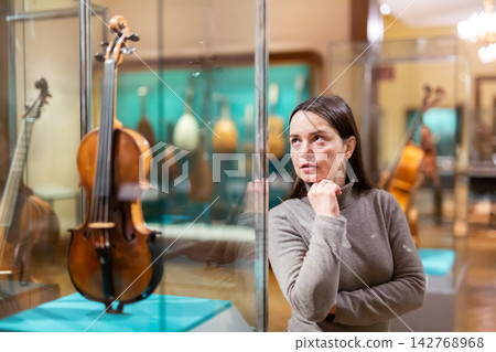Woman viewing collections of ancient musical instruments in museum Woman viewing collections of ancient musical instruments in museum 142768968