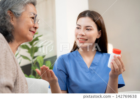 Asian woman nurse explaining medicine instruction to senior patient. Asian woman nurse explaining medicine instruction to senior patient. 142769638