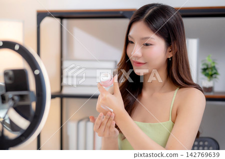 Young asian woman presenting and review cosmetic product with excitement on social media. Young asian woman presenting and review cosmetic product with excitement on social media. 142769639