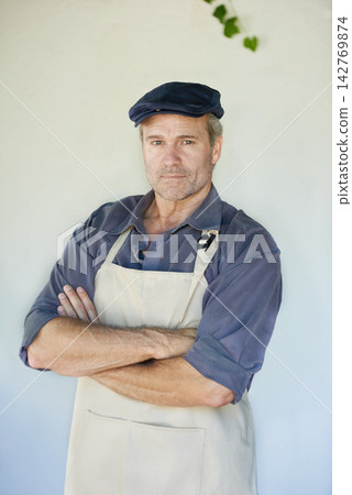 Portrait, man and confident cafe owner on wall background for small business startup manager. Face, entrepreneur or mature professional with arms crossed in apron at restaurant for barista in Germany Portrait, man and confident cafe owner on wall background for small business startup manager. Face, entrepreneur or mature professional with arms crossed in apron at restaurant for barista in Germany 142769874