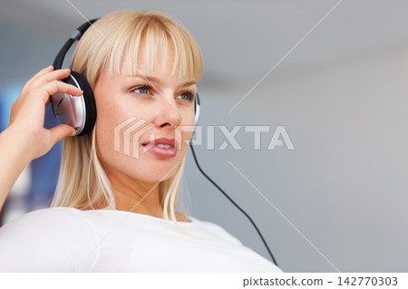 Headphones, music and thinking with woman on sofa in living room of home to relax for weekend time off. Radio, streaming and idea with serious person listening to audio playlist or sound in apartment Headphones, music and thinking with woman on sofa in living room of home to relax for weekend time off. Radio, streaming and idea with serious person listening to audio playlist or sound in apartment 142770303