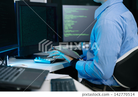 IT developer typing code on a keyboard while holding a digital tablet. Modern cybersecurity, software programming, and network analysis 142770514