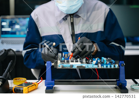 Closeup of expert soldering a green PCB board using precision tools. Ideal for electronics, circuit repair, engineering Closeup of expert soldering a green PCB board using precision tools. Ideal for electronics, circuit repair, engineering 142770531